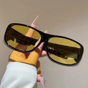 Close-up of sporty black oversized sunglasses with amber yellow lenses and wide frame