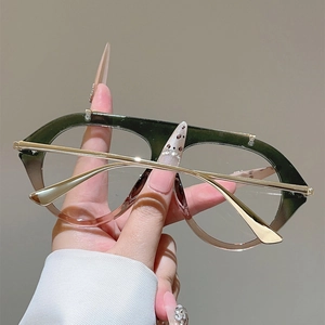 Close-up of gradient green frame glasses with thin gold metal temples in hand