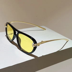 Gelbe Flieger-Sonnenbrille mit goldenen Knotenscharnieren auf einem weißen Grafikblock