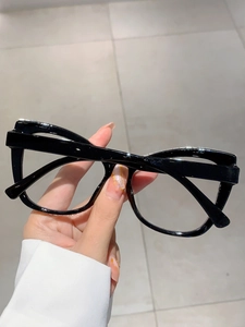 Close-up of black oversized eyeglass frames with a glossy finish held in hand