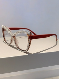Detail of cat-eye glasses featuring rhinestone trim, tortoiseshell frame and red temples