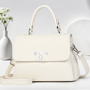 Macro view of cream lychee texture leather handbag with elegant silver TG metal logo