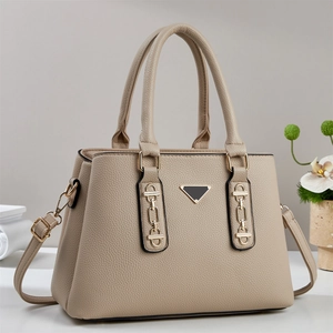 Minimalist beige pebble leather tote bag with gold chain and top handles on a clean background