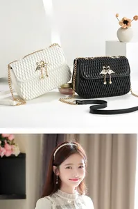Close-up of quilted shoulder bag featuring twin swan metal locks and pearl pendants