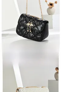 Close-up of quilted leather crossbody bags with golden swan pendants and pearl charms