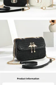 Detail of black quilted shoulder bag featuring gold swan clasp and chain strap texture