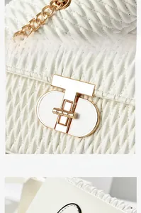 Detail of white quilted handbag featuring light gold T-shaped metal lock and chain strap