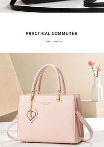 Detail of pink tote bag showing golden heart pendant with pearl and brand text