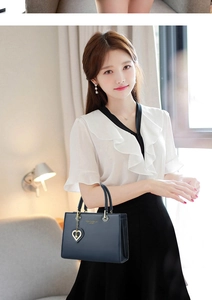 Detail of dark blue leather handbag with elegant heart charm and fashion lettering