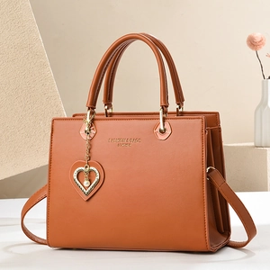 Elegant brown leather handbag for women featuring a heart pendant and minimalist design