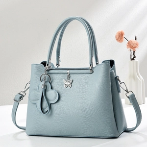 Close-up of light blue lychee pattern handbag with silver butterfly pendant and floral charm