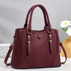 Elegante borsa bordeaux con motivo a coccodrillo e dettagli dorati su sfondo minimalista