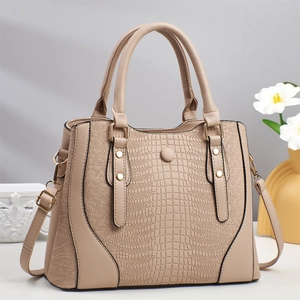Dettaglio borsa tote beige con texture a coccodrillo e rifiniture in metallo dorato