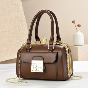 Detail of brown leather handbag with pearl clasp and gold hardware in elegant setting
