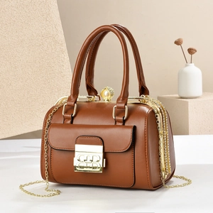 Close-up of brown Boston bag with golden chain, pearl clasp and metallic logo lock