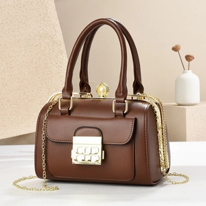 Detail of brown leather doctor bag with golden clasp, pearl accent and chain strap