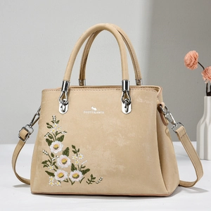 Close-up of beige leather tote bag with daisy embroidery and silver metal hardware details