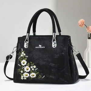 Close-up of black tote bag with intricate floral embroidery and silver metal hardware