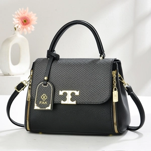Detail of black pebbled leather handbag with woven flap and gold metal hardware