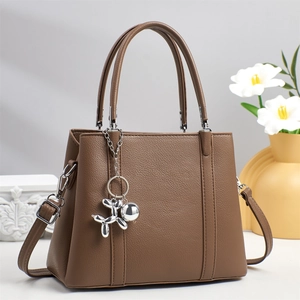 Brown lychee-grain leather tote bag detail with adjustable strap and balloon dog charm