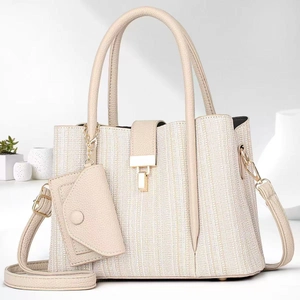 Detail of cream white tote bag with textured fabric, gold clasp and small coin purse charm