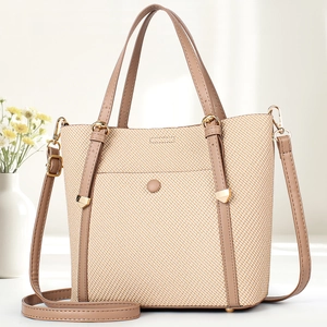 Detail of woven tote bag texture with brown leather straps and gold metal hardware