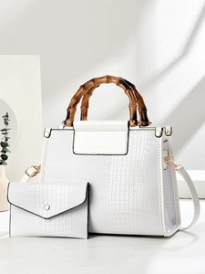 Detail showing white crocodile texture and vintage bamboo handles on a large shoulder bag