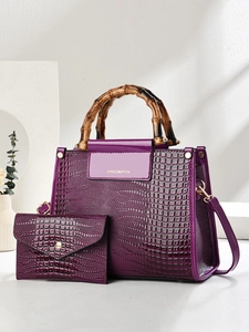 Detail of purple crocodile-patterned bag with bamboo handle and matching small clutch