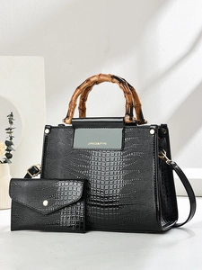 Detail of black crocodile texture handbag with unique brown bamboo handles and a matching pouch
