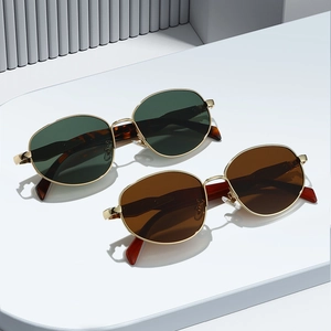 Retro round metal sunglasses with cat-eye lenses in green and tea colors on a pedestal