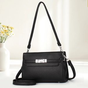 Detail of black pebbled leather texture on crossbody bag with silver twist lock