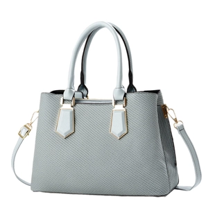 Light blue woven texture tote bag with golden hardware and leather straps on white background