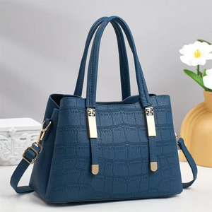 Large dark blue crocodile texture tote bag with gold metal accents on a grey background