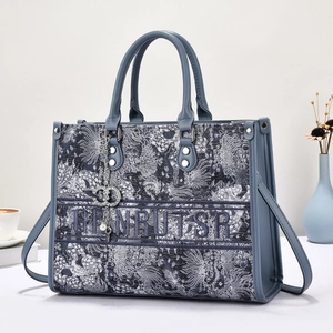 Detail of grey-blue floral embroidery on tote bag with GIANRUTSR logo and leather handles
