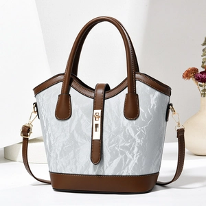 Detail of a light blue marble-textured bucket bag with brown leather handles and gold lock