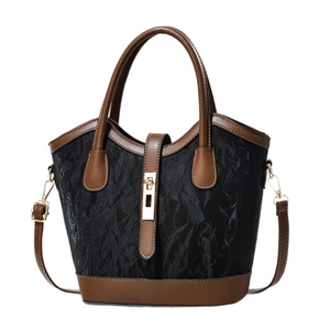 Elegant black textured bucket bag with brown leather trim and gold metal clasp