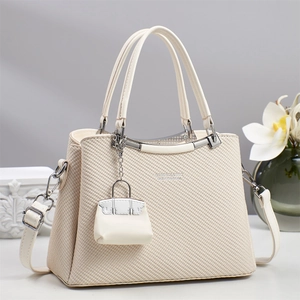 Detail of cream leather handbag with woven texture and matching mini pouch charm
