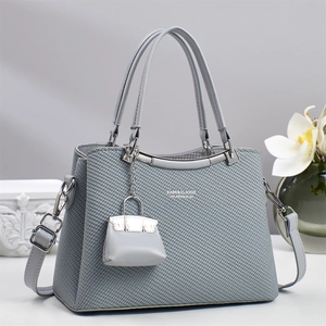Detail of grey woven crossbody bag with silver hardware and mini pouch charm decoration