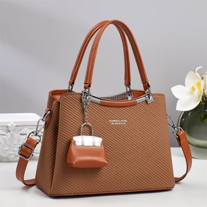 Detail of woven brown handbag with BABK & CLASSIC text and mini bag charm accessory
