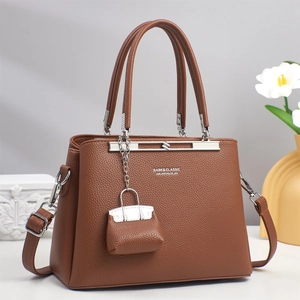 Elegant caramel brown lychee leather handbag for women featuring a mini bag charm detail