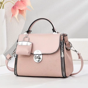 Détail du sac bandoulière rose avec tissu texturé, fermoir rotatif et breloque élégante