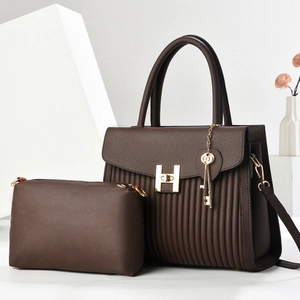 Détail du sac cabas en cuir marron avec fermoir H doré et sa pochette assortie sur socle