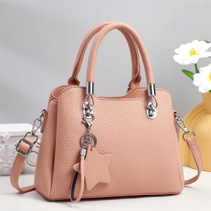 Pink pebbled leather tote bag with star charm and detachable strap on white display pedestal
