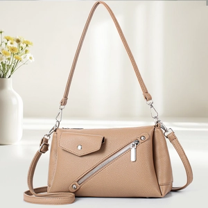 Detail of light brown lychee grain leather handbag with silver zipper and double straps