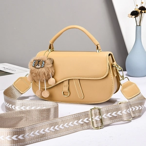Chic khaki saddle bag with patterned wide strap and plush lion charm in soft lighting