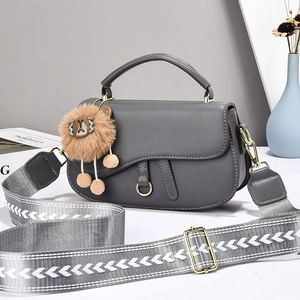 Detailed view of grey saddle bag with golden D-ring hardware and printed wide strap