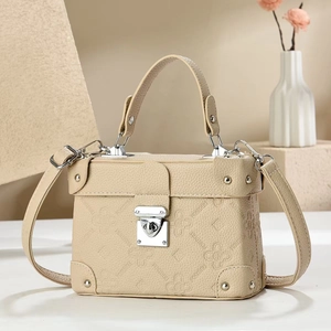Beige faux leather trunk bag with clover embossing and silver clasp on a stylish pedestal