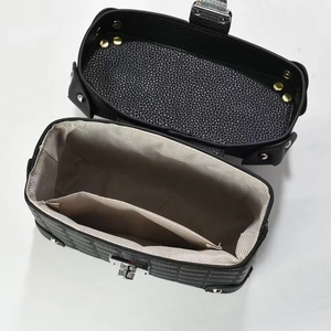 Detail of black pebbled leather handbag with silver rotary lock and herringbone lining
