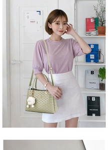 Detail of sage green crossbody bag with gold logo and cute white lamb plush pendant