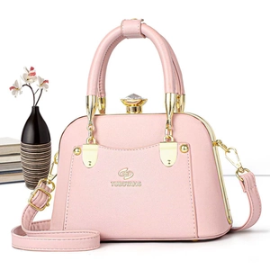 Detailed view of pink shell-shaped tote bag with gold hardware and gemstone closure